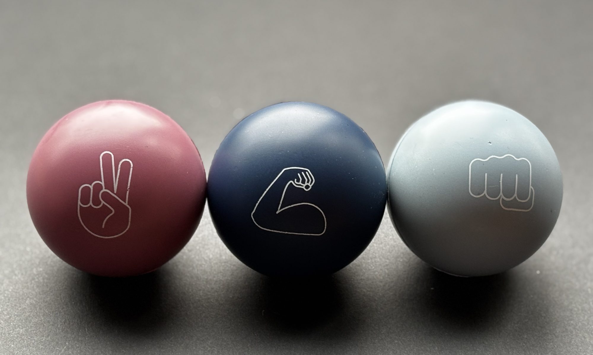 Stressbälle mit Peace-Zeichen, Bizeps und Faust als Motive.